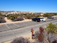A parking lot with three cars parked in spots. A small brown sign says, Group Campsites. 