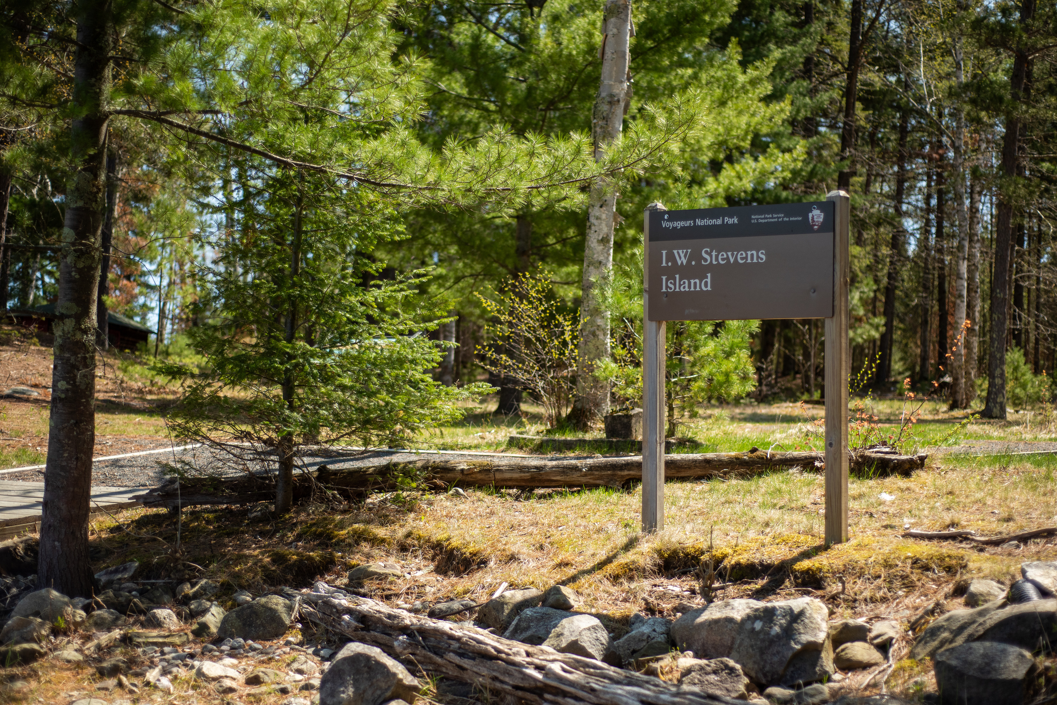 Photograph of sign with "I.W. Stevens Island" printed in white lettering, with trees in the background.