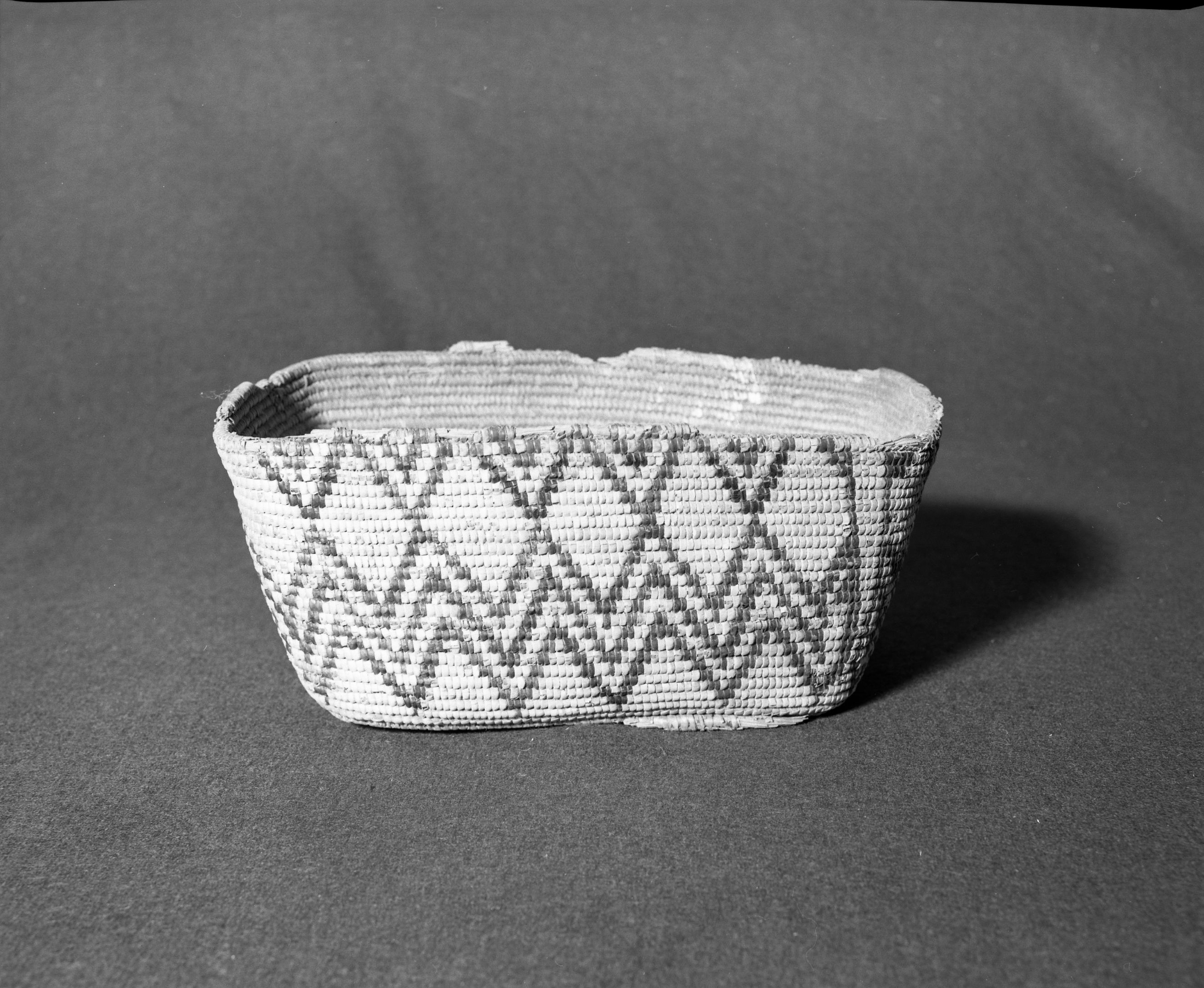 Marie Rozier Collection, Catalog No. 194. Object: Salish basket. Dimensions: 12 x 7 x 5 1/2". Materials: Cedar root, cherry bark, grass. Technology: Remnants of footed base on bottom. Collection History: Probably made for sale. Reportedly obtained from Kalapine? Jenny? Gift Mrs. Mae Wilson Austin who got it from her mother Mrs. Alice Wilson. Photographed by Michael Dixon, December 1982. Catalogued by Craig Bates and Barbara Beroza. Yosemite Collections, National Park Service.