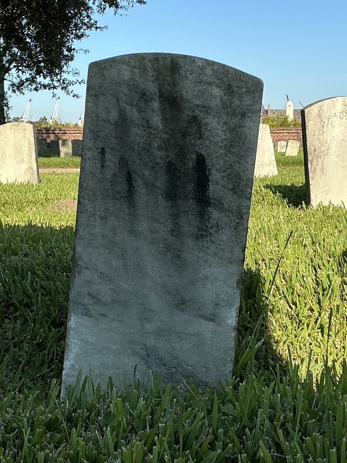 Back of historic upright marble headstone with recessed shield face.