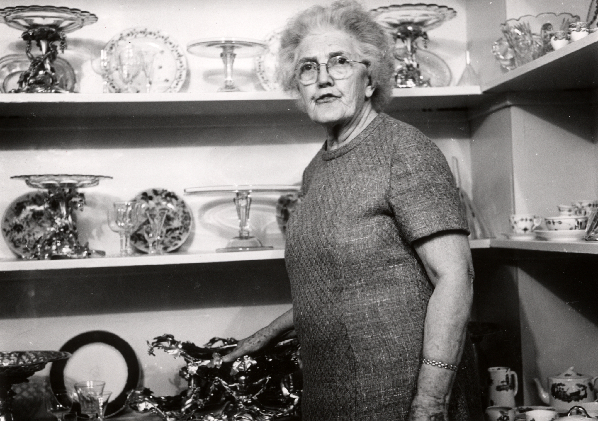 Wilhelmina Harris standing in front of shelves with various dishes and glassware.
