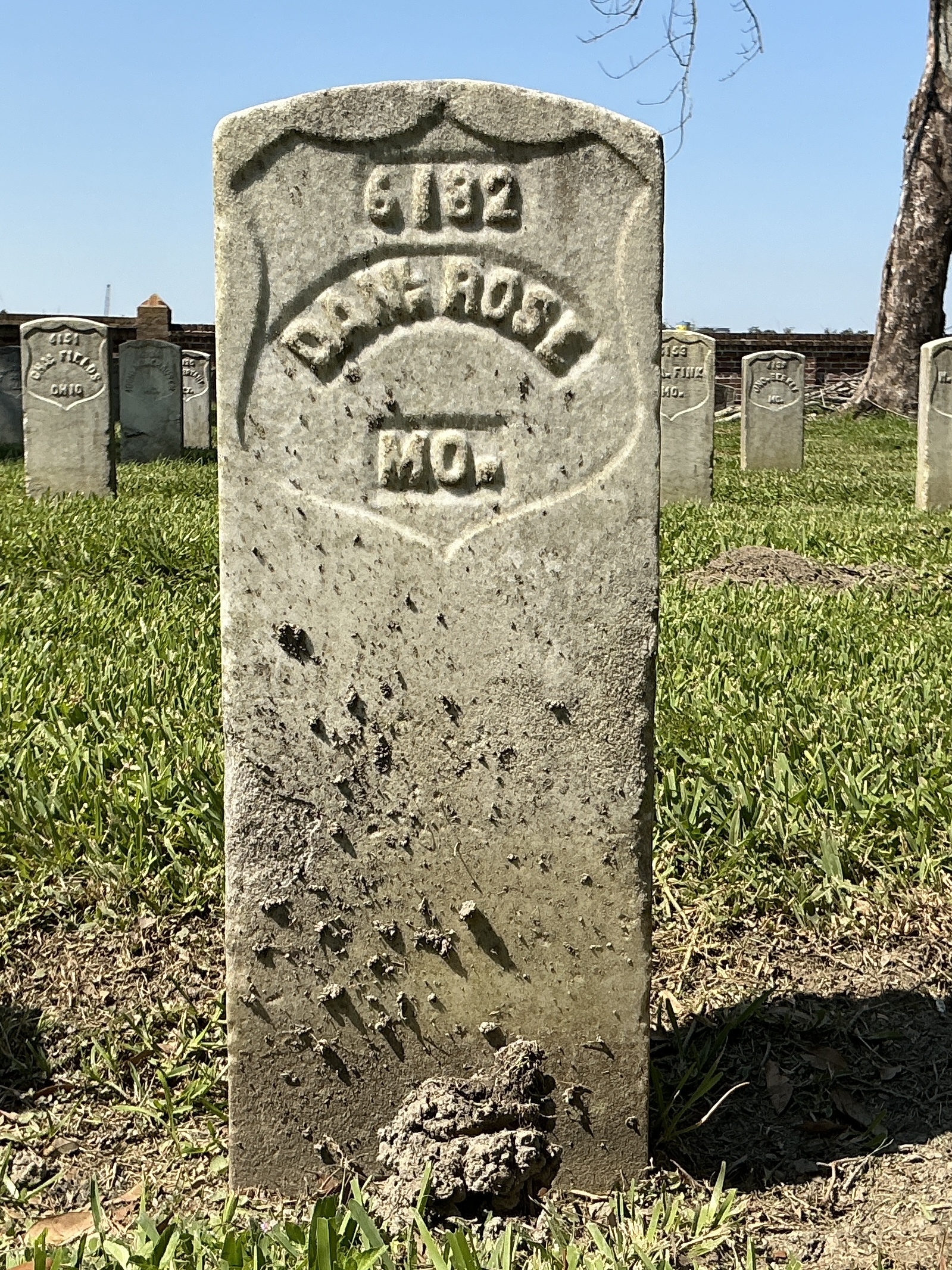 Front of historic upright marble headstone with recessed shield with recessed lettering face.