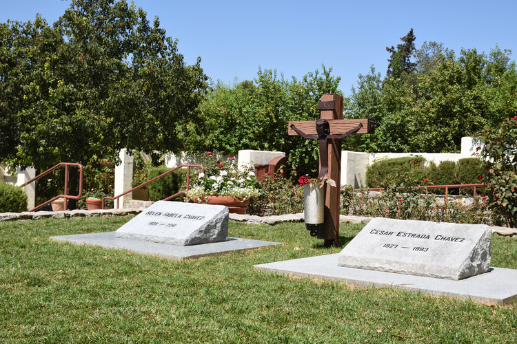 Between two graves is a rustic wooden cross with a human figure attached in iron.