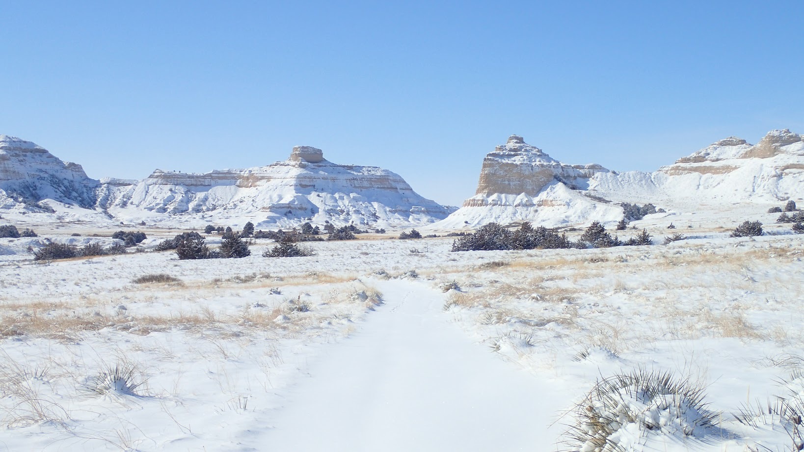 A snow covered trial with  Michell Pass in the background 
