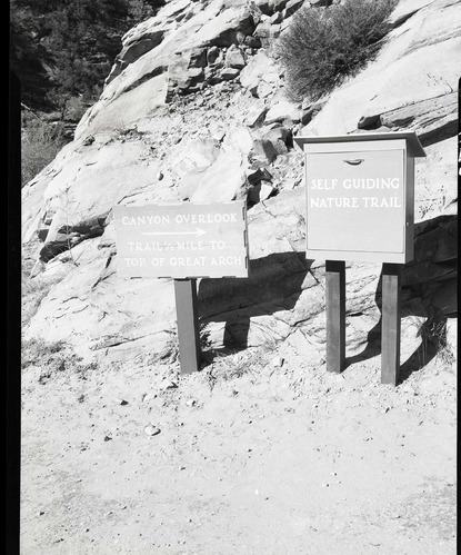 Trail sign and leaflet box for self-guiding nature trail at Canyon Overlook Trailhead near large tunnel.
