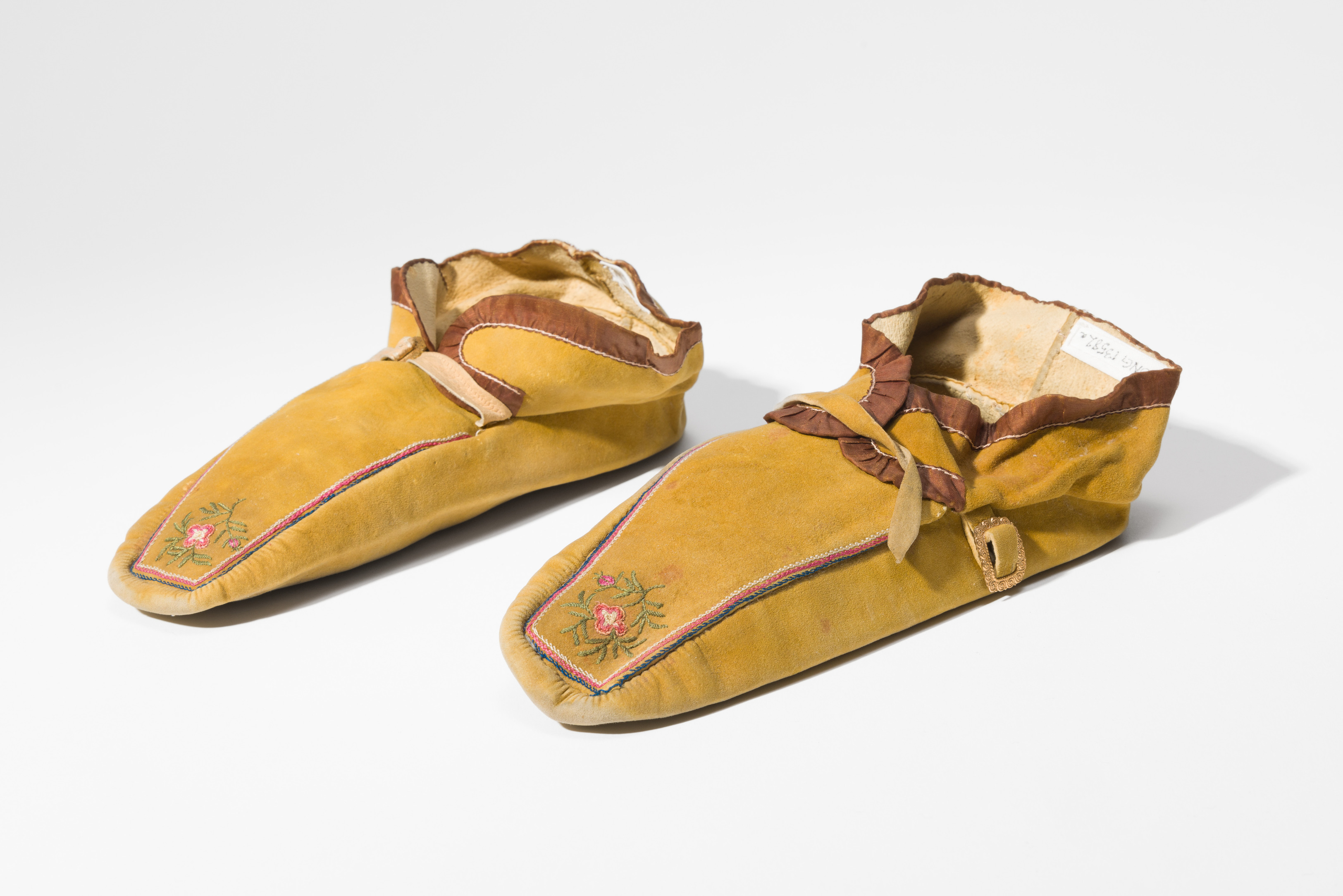 Pair of yellow moccasins with embroidered flower decoration on the toes.