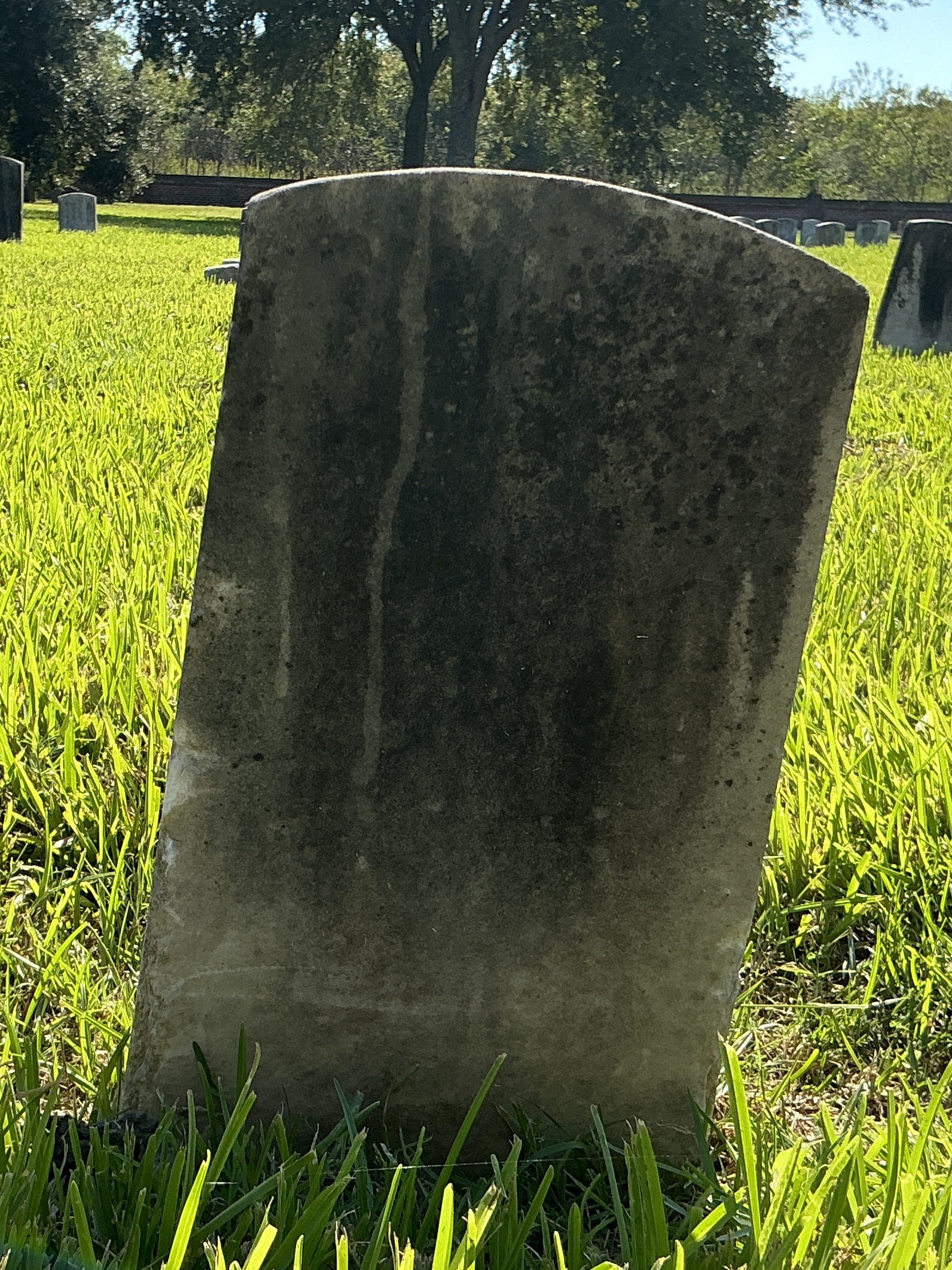 Back of historic upright marble headstone with recessed shield with recessed lettering face.