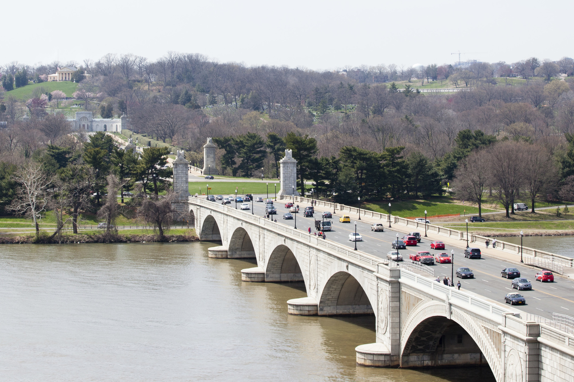 Arlington Memorial Bridge crosses over the Potomac, several cars drive across it.