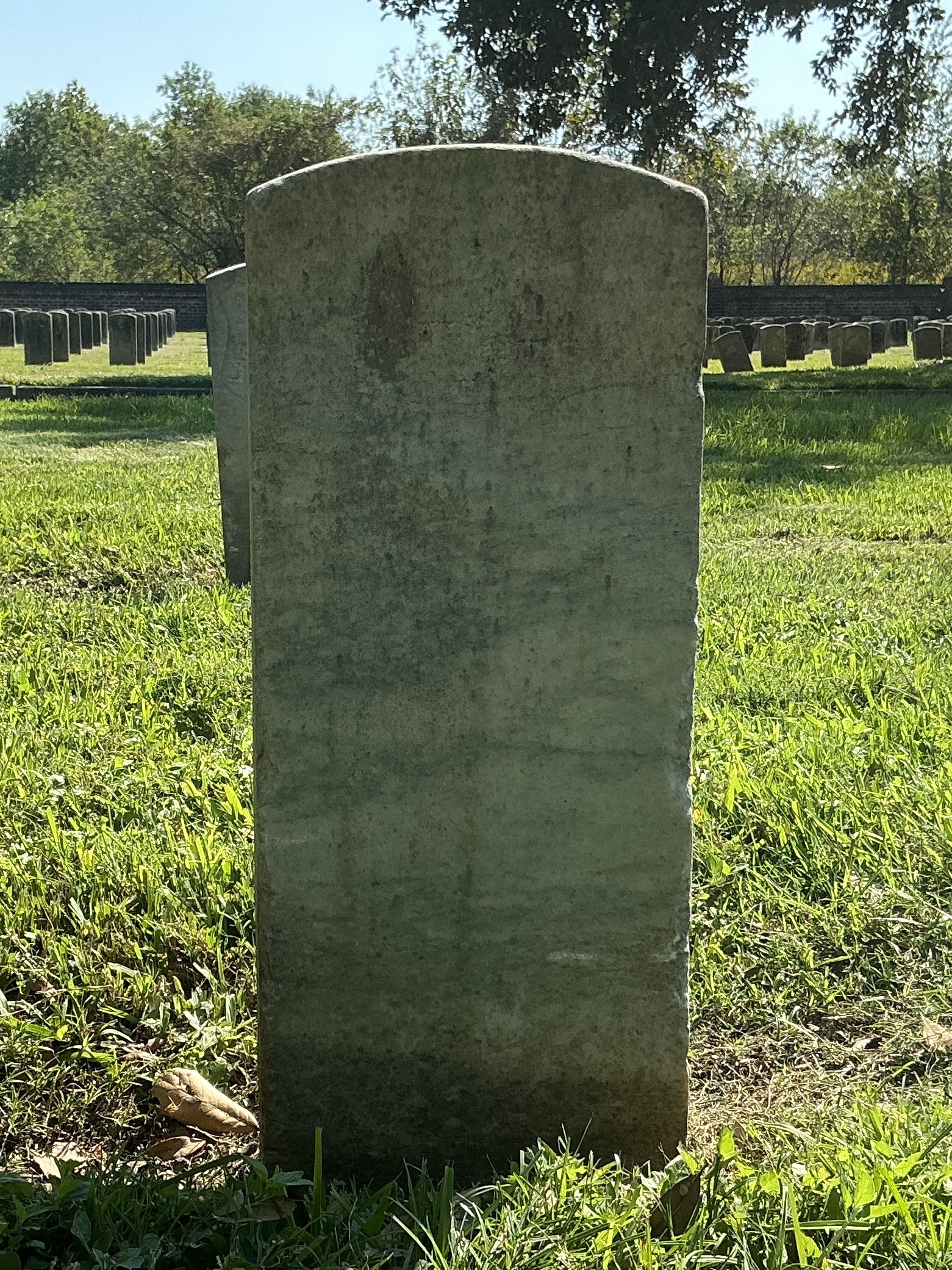 Back of historic upright marble headstone with recessed shield with recessed lettering face.