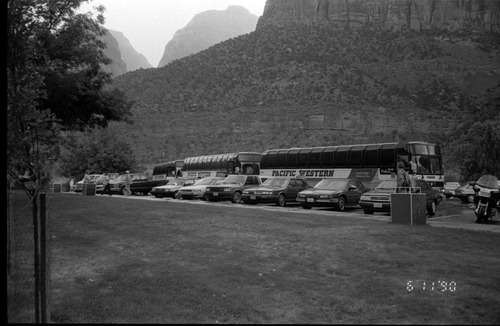 Buses and cars parked in the lot in front the of the headquarters building.