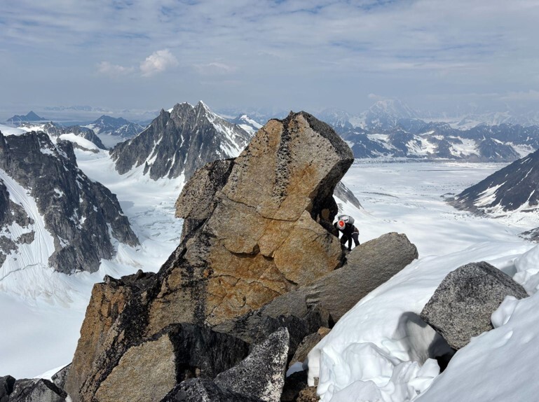 Range climbs a rocky outcrop with the mountain range in the distance