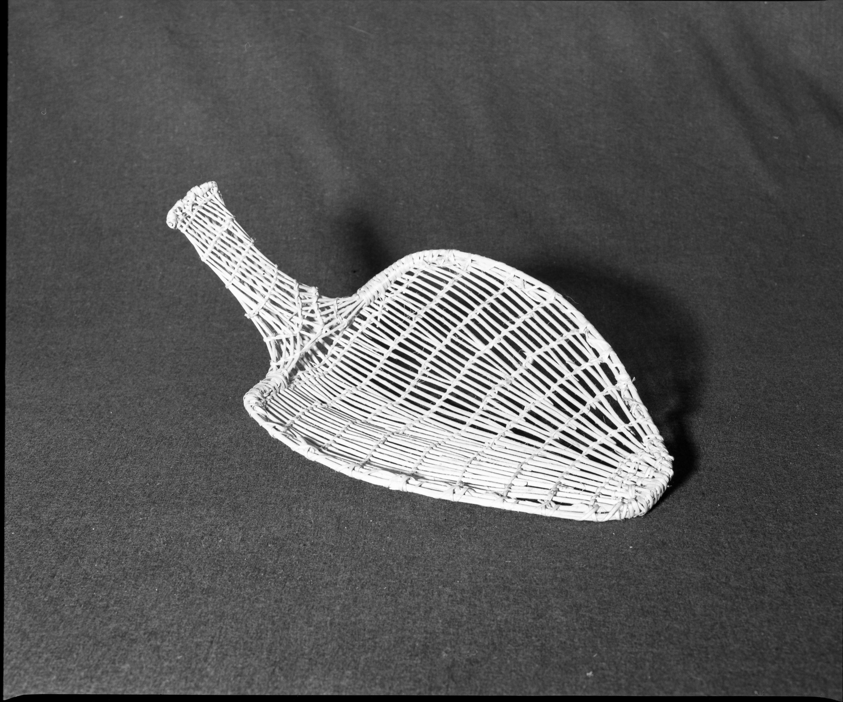 Marie Rozier Collection, Catalog No. 148. Object: Washoe seed beater. Dimensions: 12 x 9"; Handle 6". Materials: Willow shoots. Technology: Plain twined, down to right slant of turns, rimstick bound with split willow shoots. Collection History: Made by Enie Cornbread. Photographed by Michael Dixon, December 1982. Catalogued by Craig Bates and Barbara Beroza. Yosemite Collections, National Park Service.