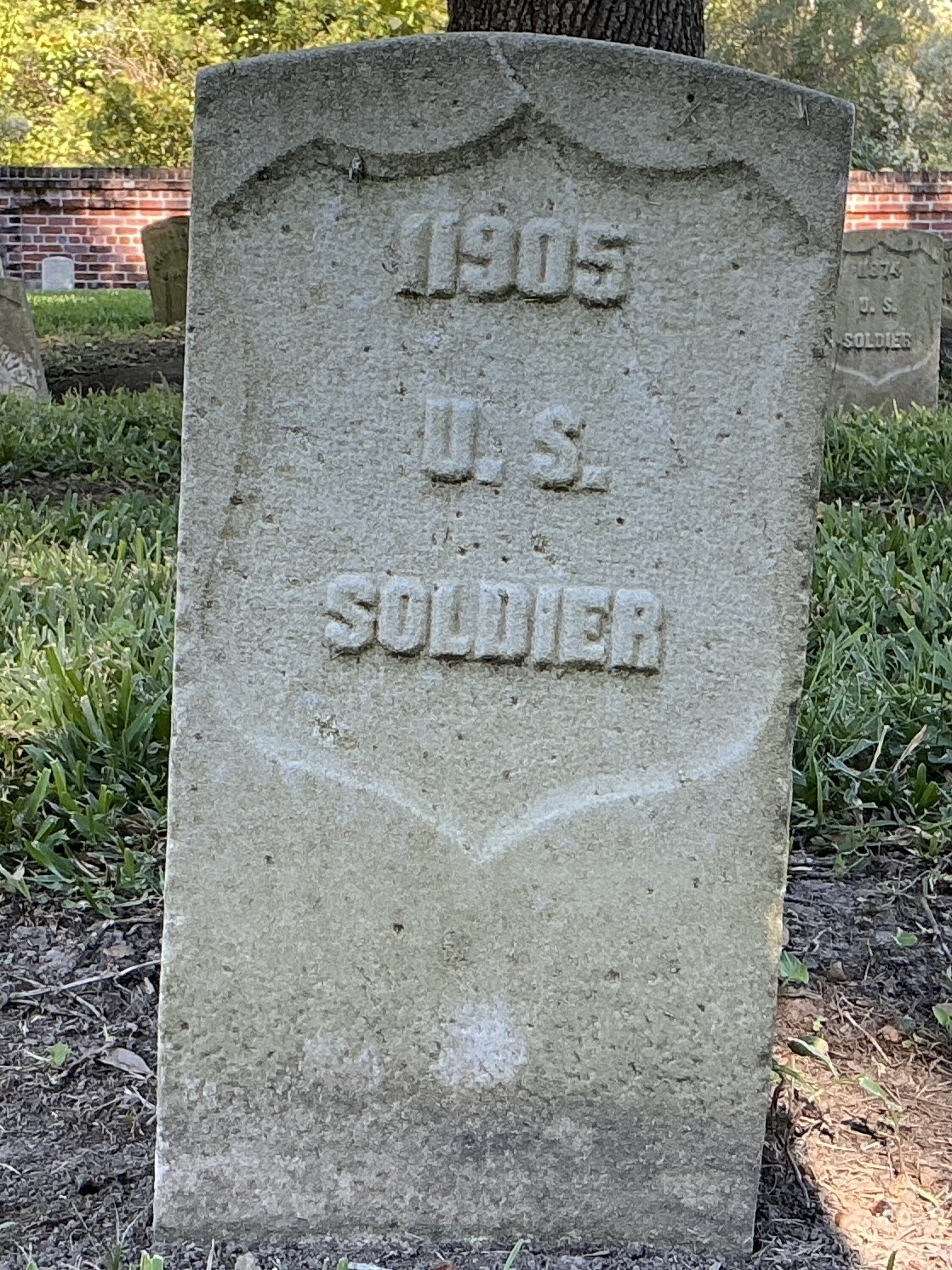 Front of historic upright marble headstone with recessed shield face.