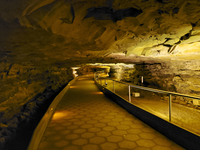 A paved trail travels through a narrow cave passage. 