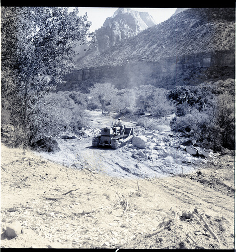 Clearing the right-of-way for new highway, from South Entrance Station to Virgin River Bridge. Bulldozer clearing and scraper collecting top soil (in background).
