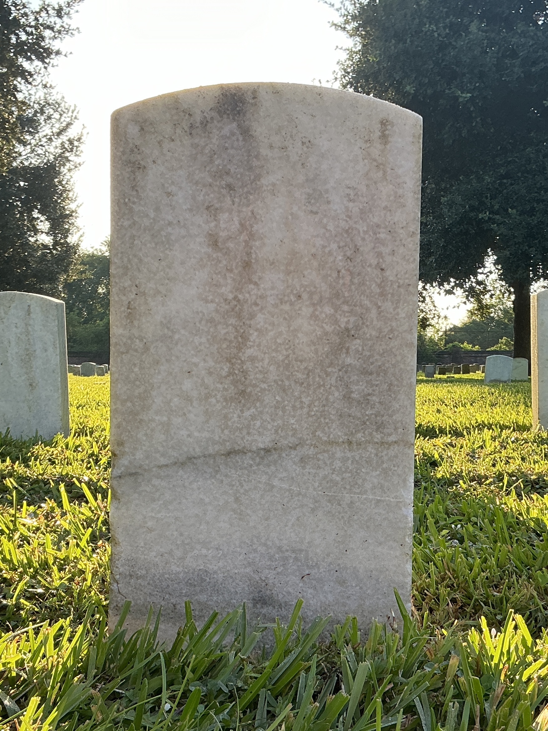Back of historic upright marble headstone with recessed shield face.