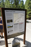 A grey panel sits in a brown metal frame. There is text and images on the panel informing visitors about the Don Cecil trail.