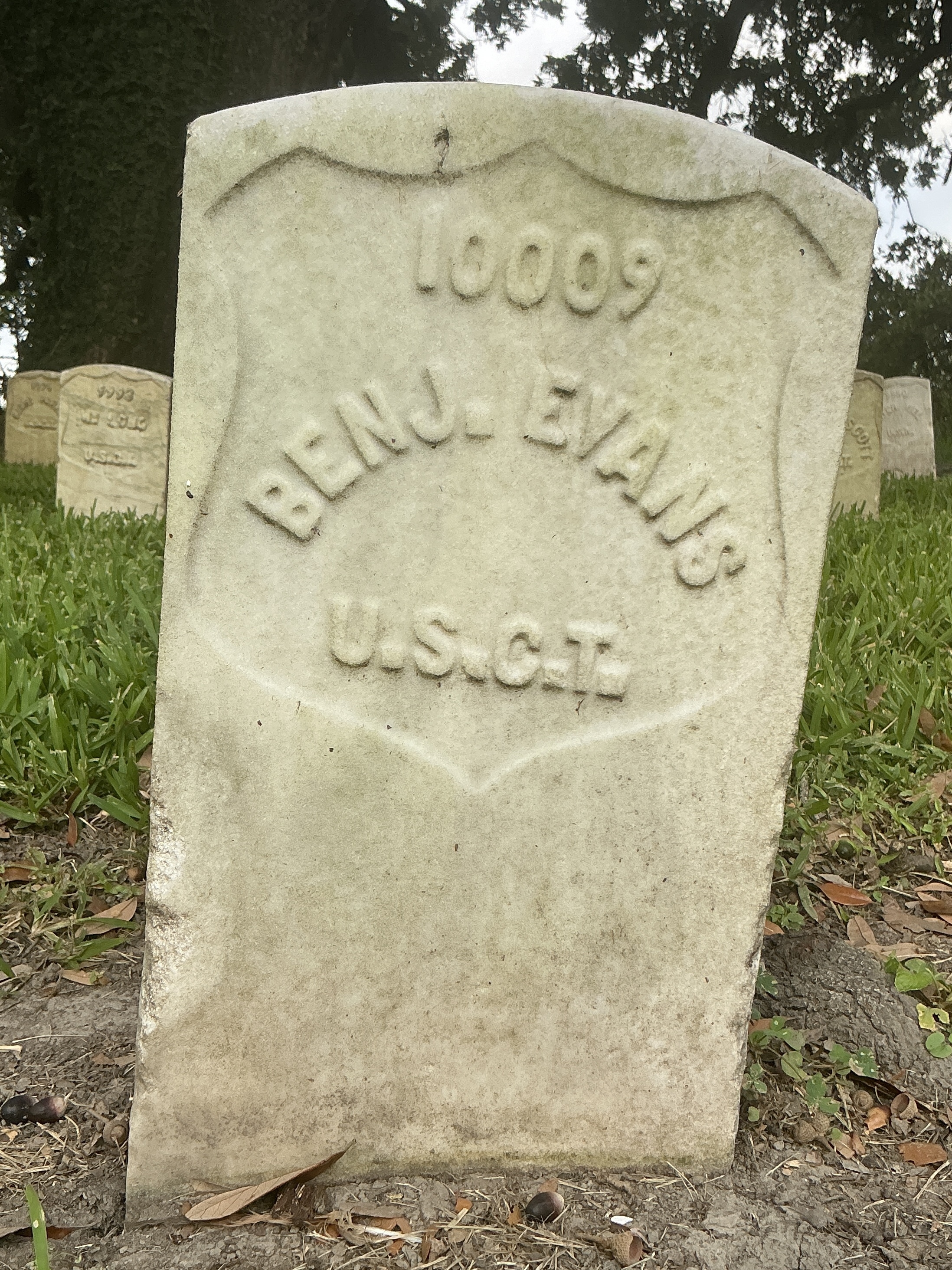 Front of historic upright marble headstone with recessed shield face.
