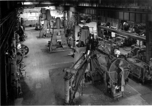 Interior of large industrial building with four massive hammers used to make chain. 