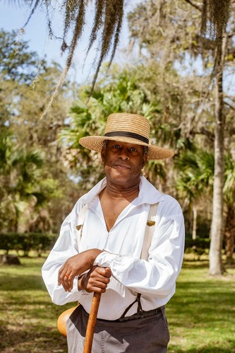 person in outdoors with straw hat and historical clothes on
