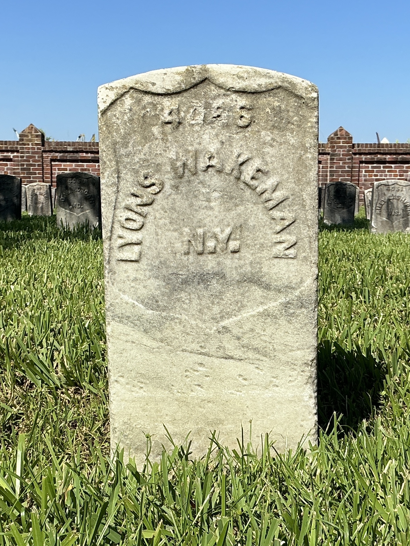 Front of historic upright marble headstone with recessed shield face.