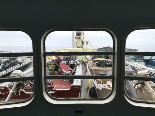 Bow of larger boat with view of four smaller fishing boats being transported. 