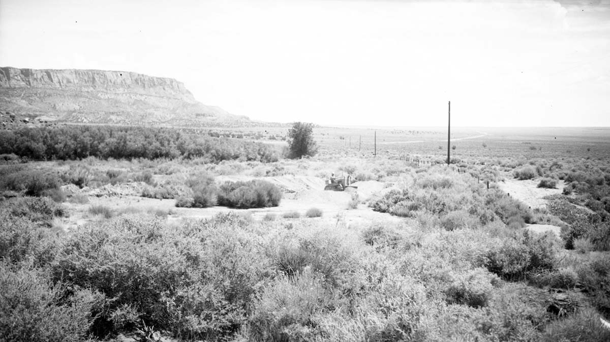 Deseret Telegraph Company telegraph pole. Sixth standing pole, Site E-16 approximately 2.5 miles west of Pipe Spring National Monument, and 0.5 mile north of present road. Man working on tractor in distance.