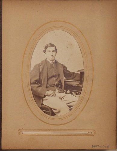Black and white photograph of young man seated at desk.