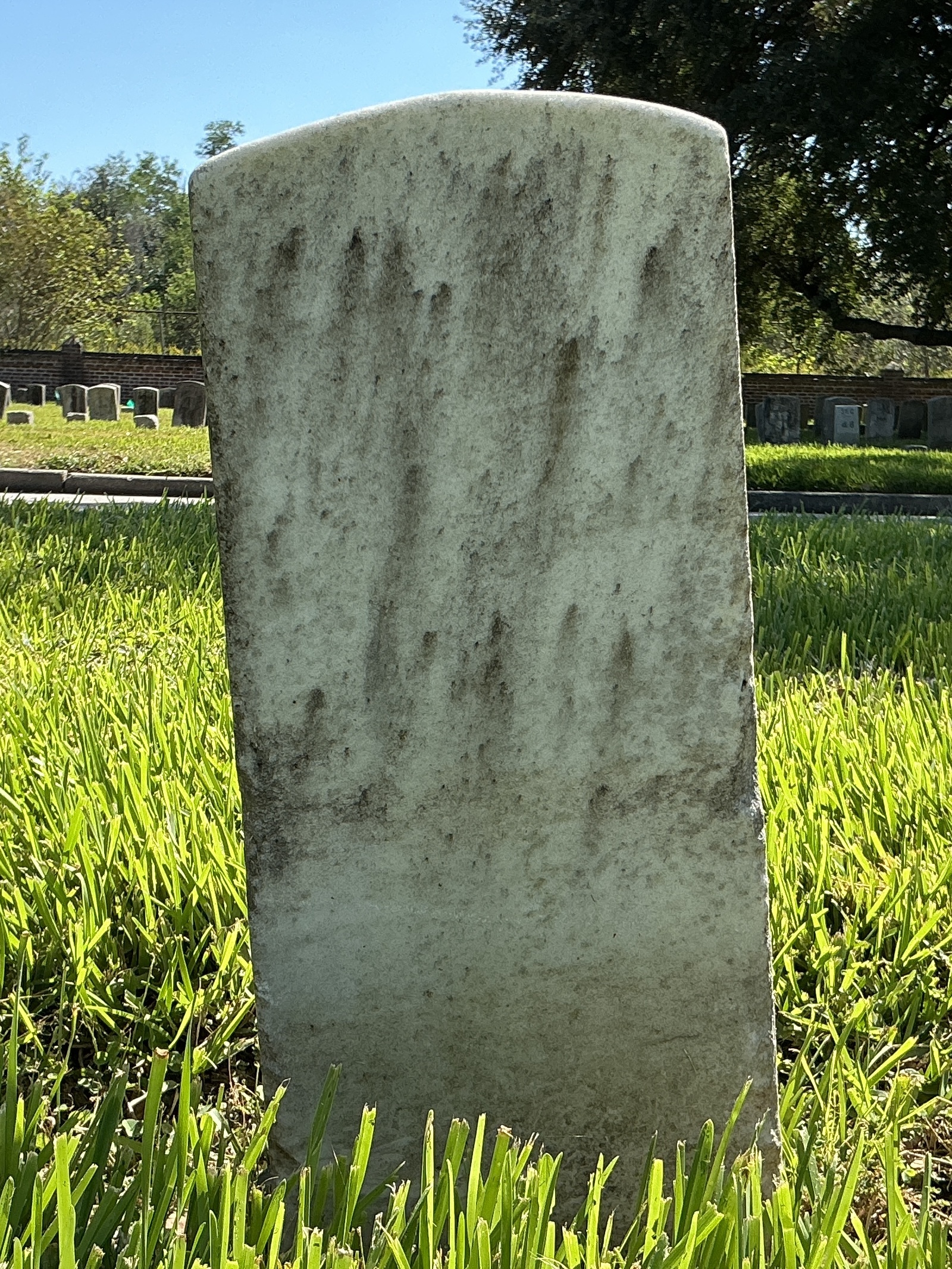 Back of historic upright marble headstone with recessed shield face.