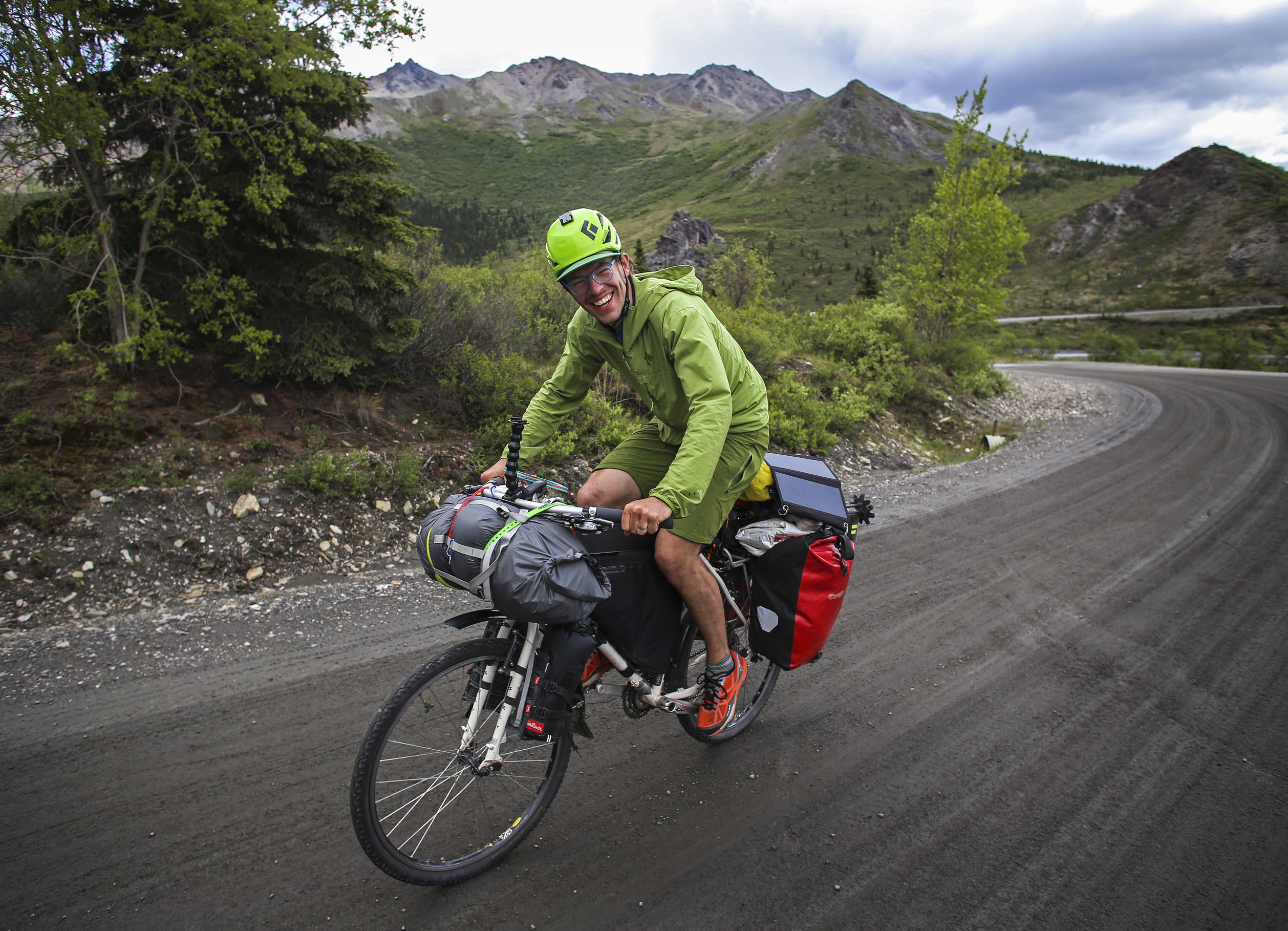 a smiling man riding a bike on a gravel road