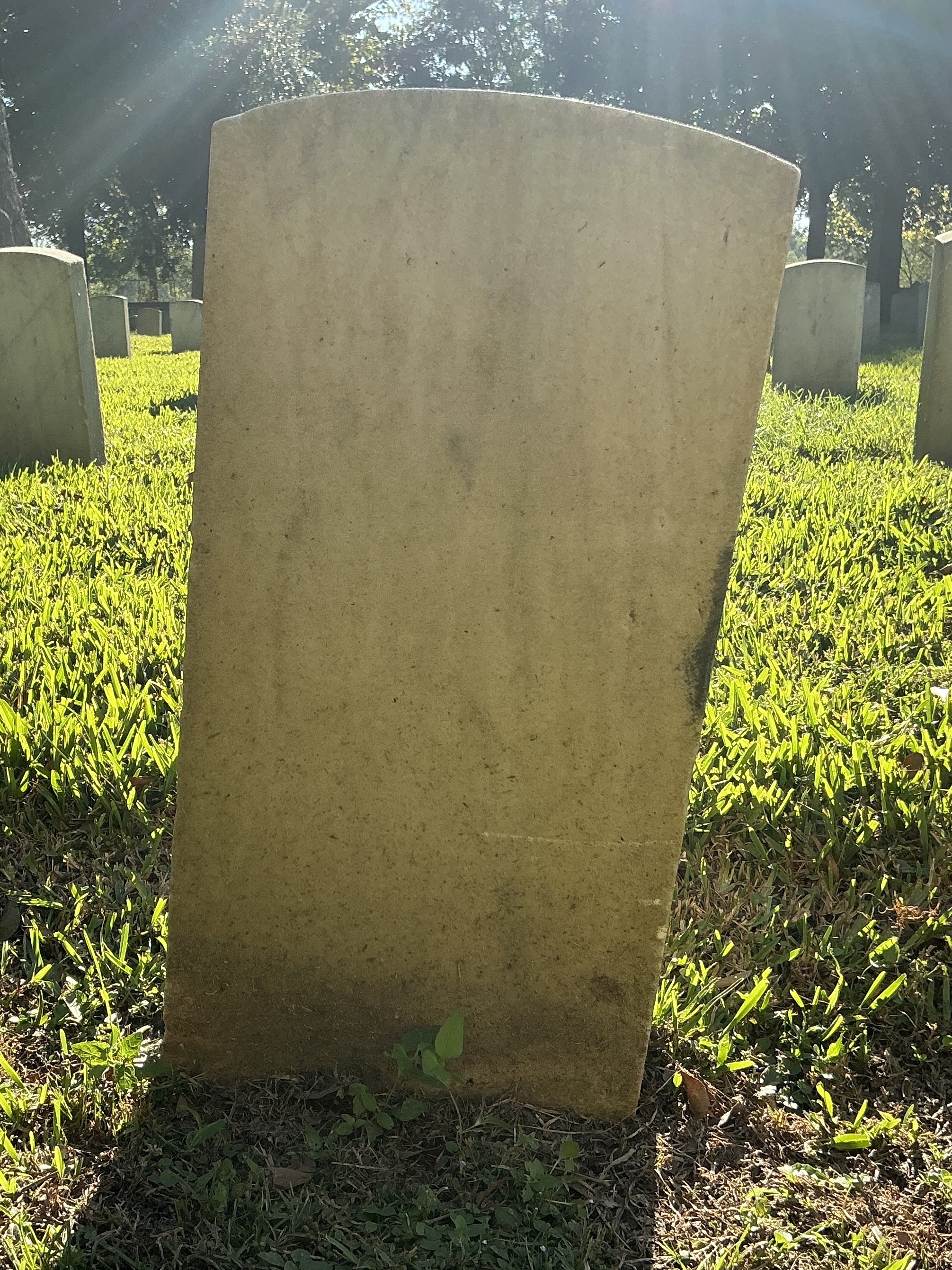 Back of historic upright marble headstone with recessed shield face.
