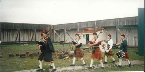 Men in traditional Scottish clothing playing instruments such as bagpipes and rdums
