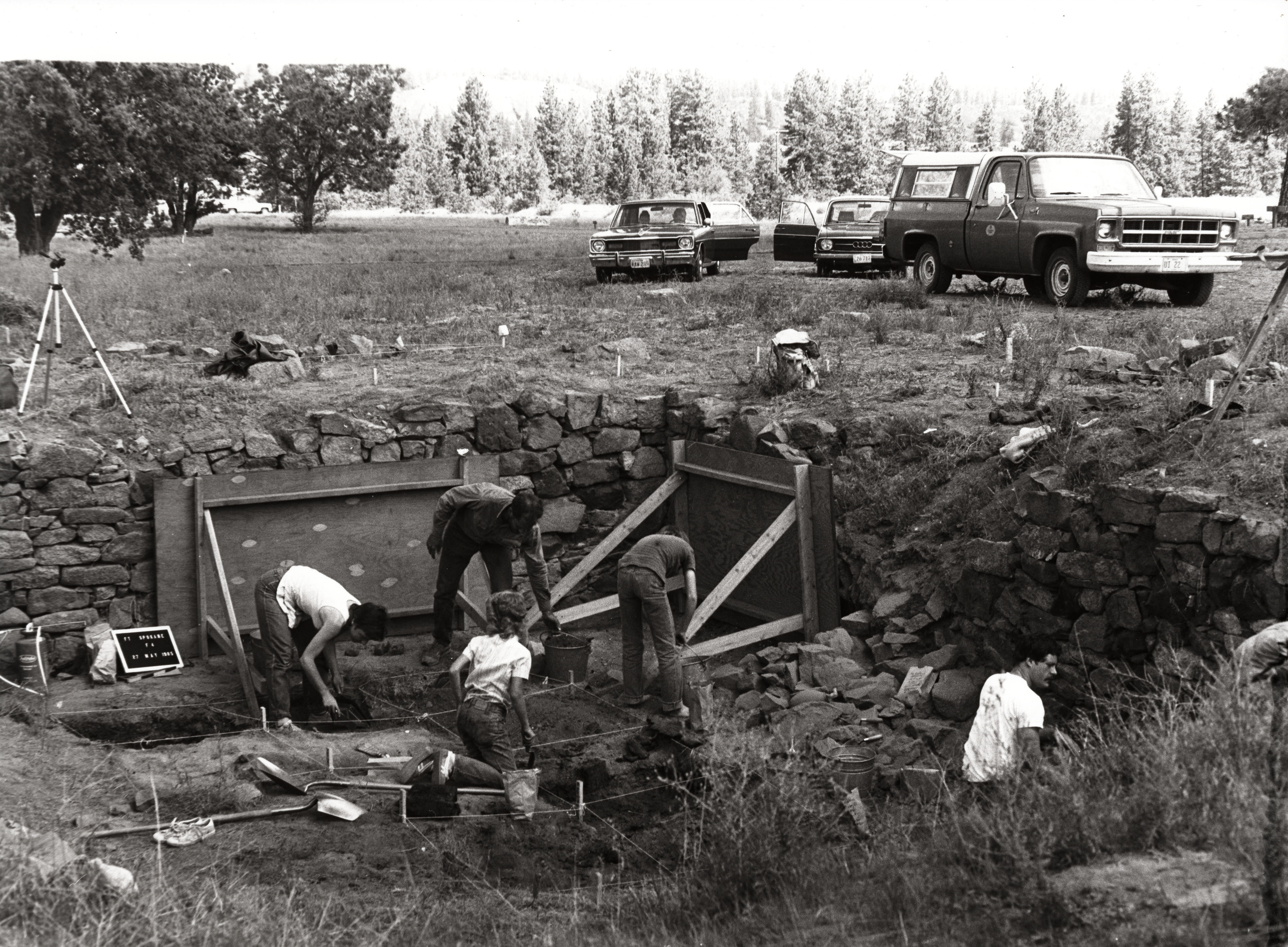 Black and white photograph of five people at an archeological dig
