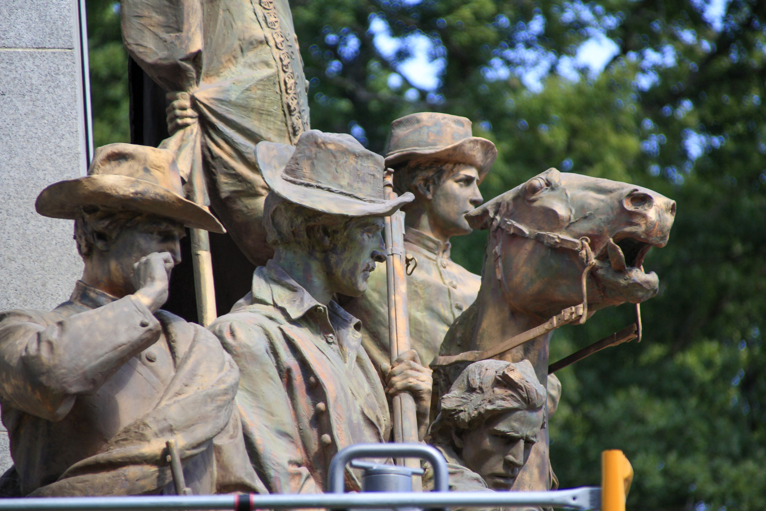 A statue showing four Civil War soldiers with the patina washed off looking brown and rusty.