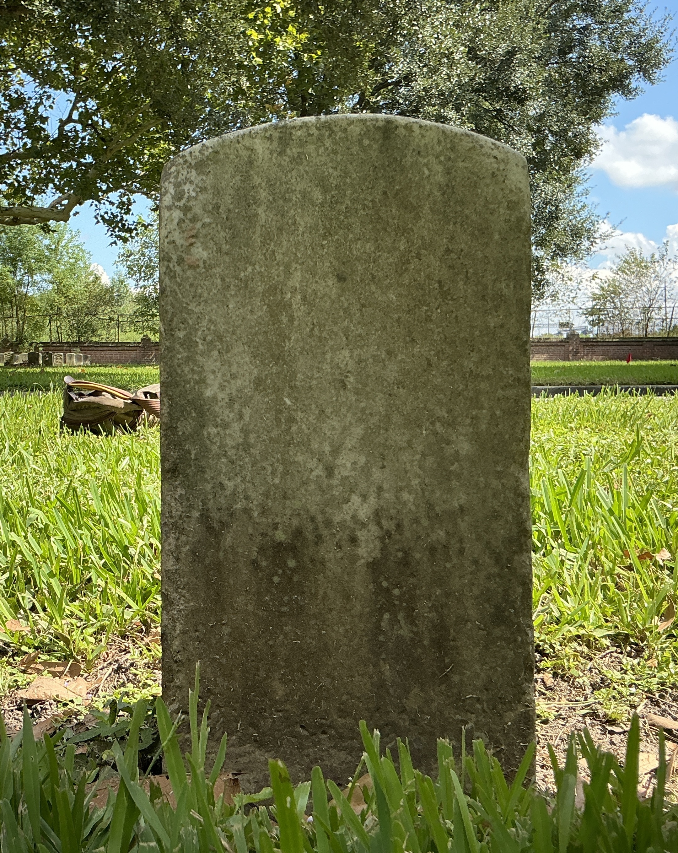Back of historic upright marble headstone with recessed shield face.