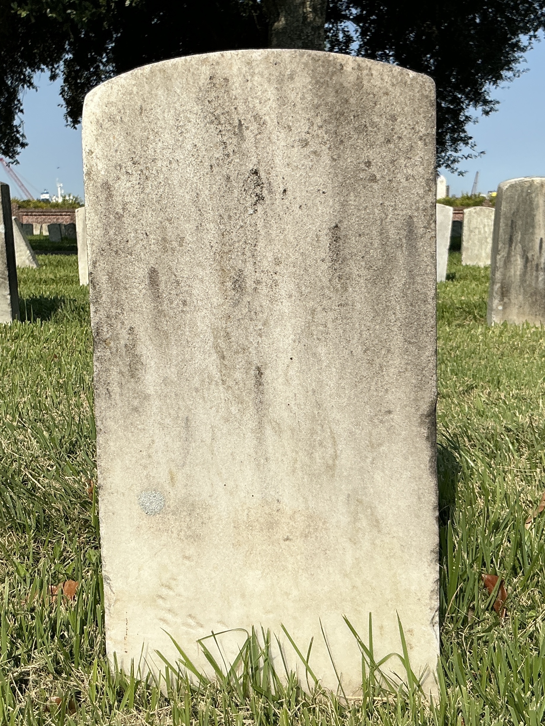 Back of historic upright marble headstone with recessed shield with recessed lettering face.