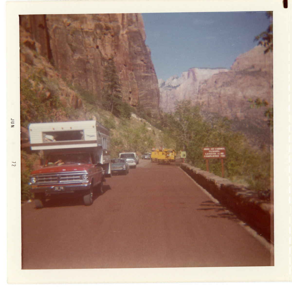 Vehicles driving down road with construction vehicle on opposite side during chipsealing of Zion roads.