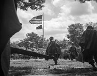 Five statues of Korean War soldiers stand in fields at the Korean War Veterans Memorial. An American flag and a Prisoners of War flag wave in the distance. 