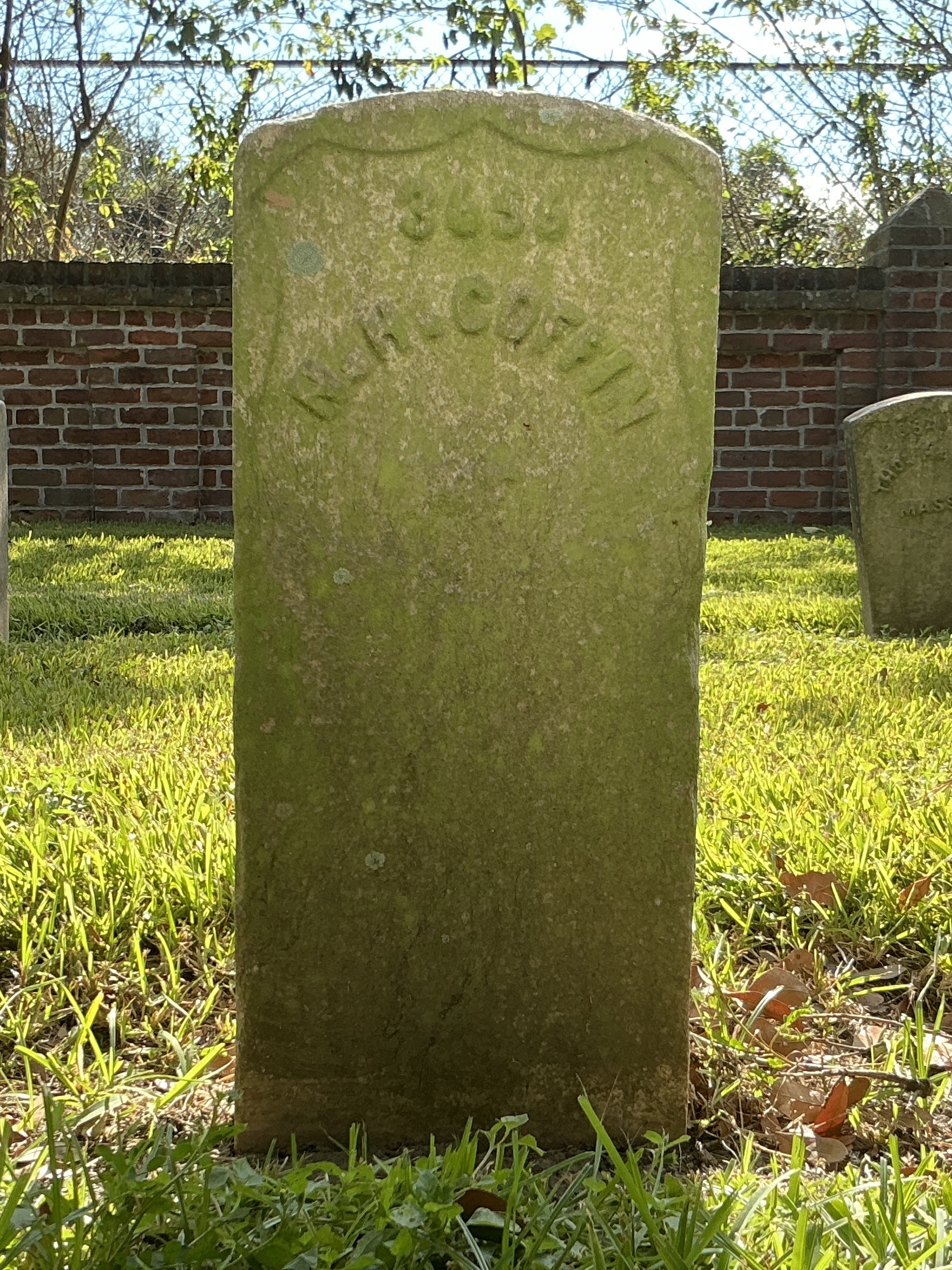Front of historic upright marble headstone with recessed shield with recessed lettering face.