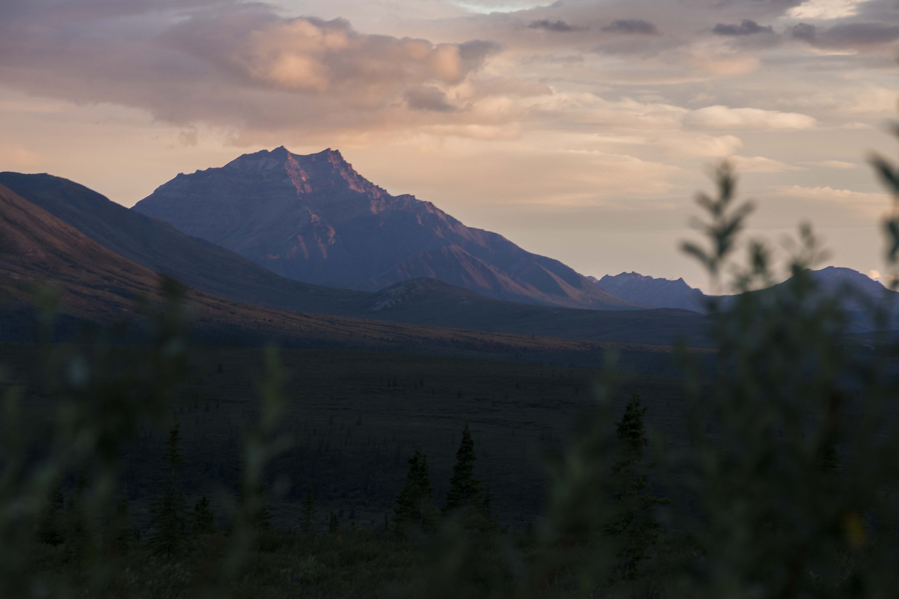 a mountain with a double peak tinged pink by the setting sun
