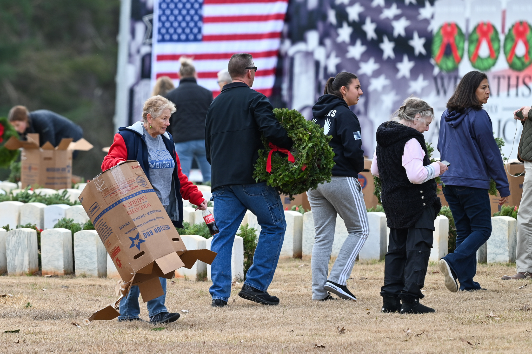 Volunteers placing wreaths in front of headstones.