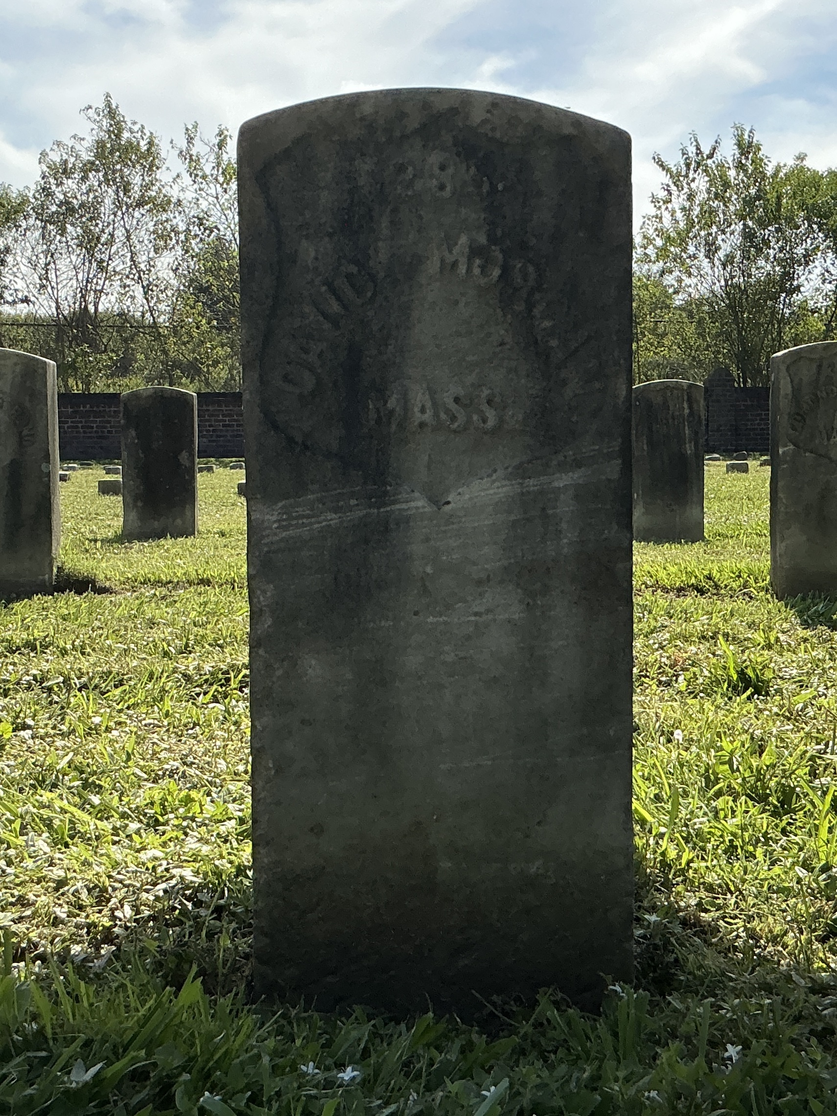 Front of historic upright marble headstone with recessed shield face.