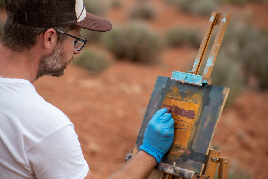 an artist marks with pastels on a wood board
