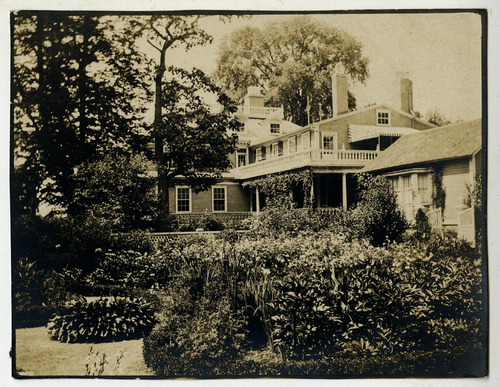 Black and white photograph of garden with Georgian mansion in background.