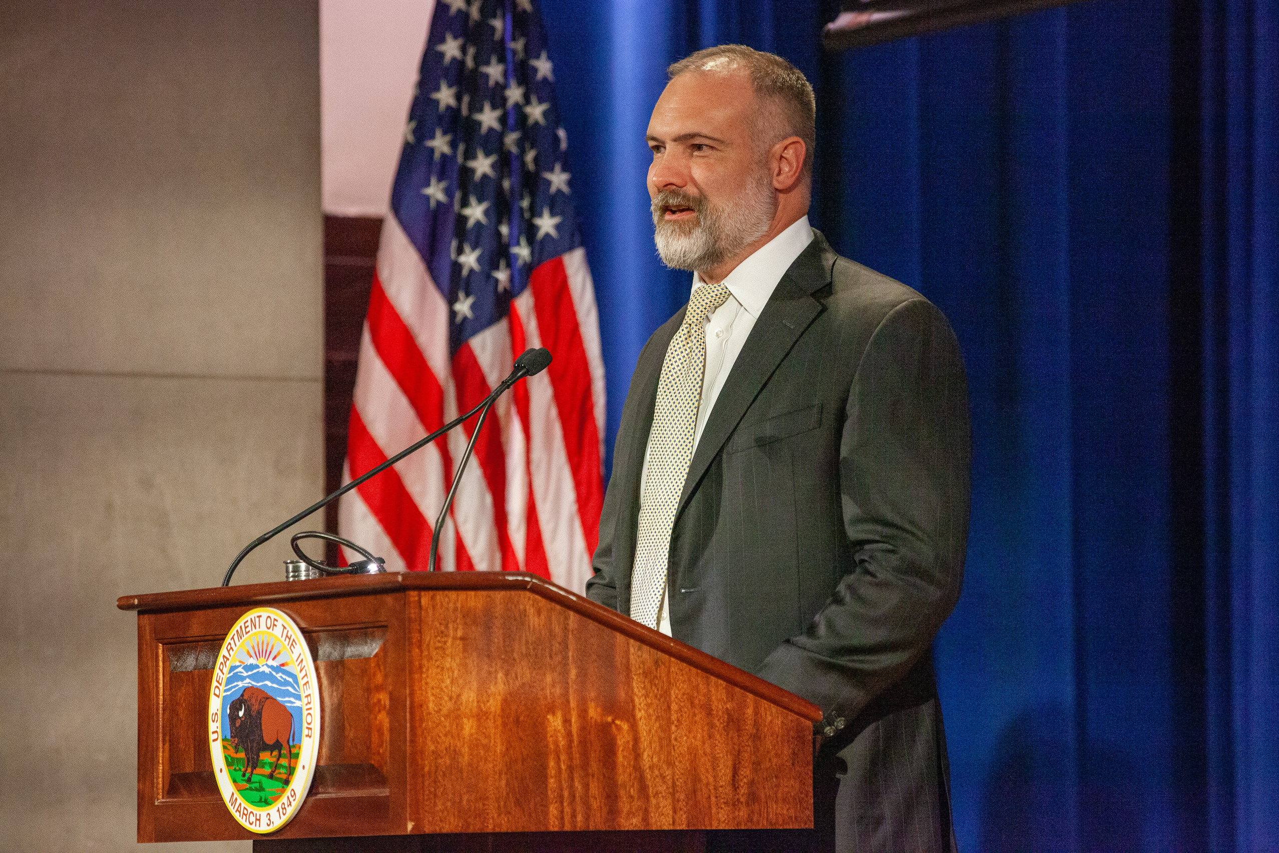Deputy Secretary of the Interior Tommy Beaudreau speaks on a podium at the 2022 National Park Service Award Ceremony in a suit. 