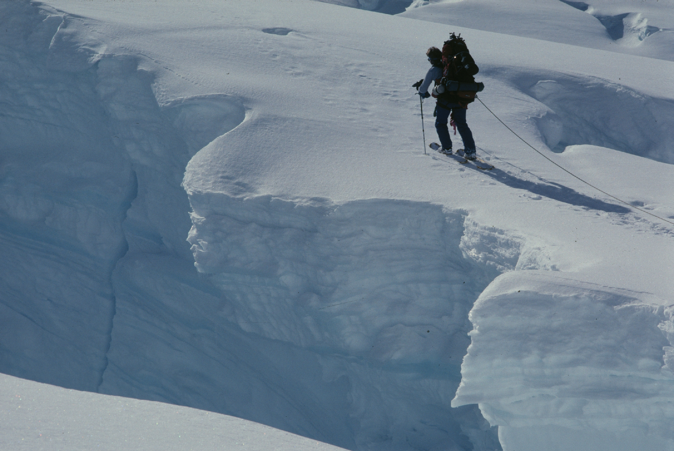 a mountaineer skis near the edge of a snowy deep crevasse 