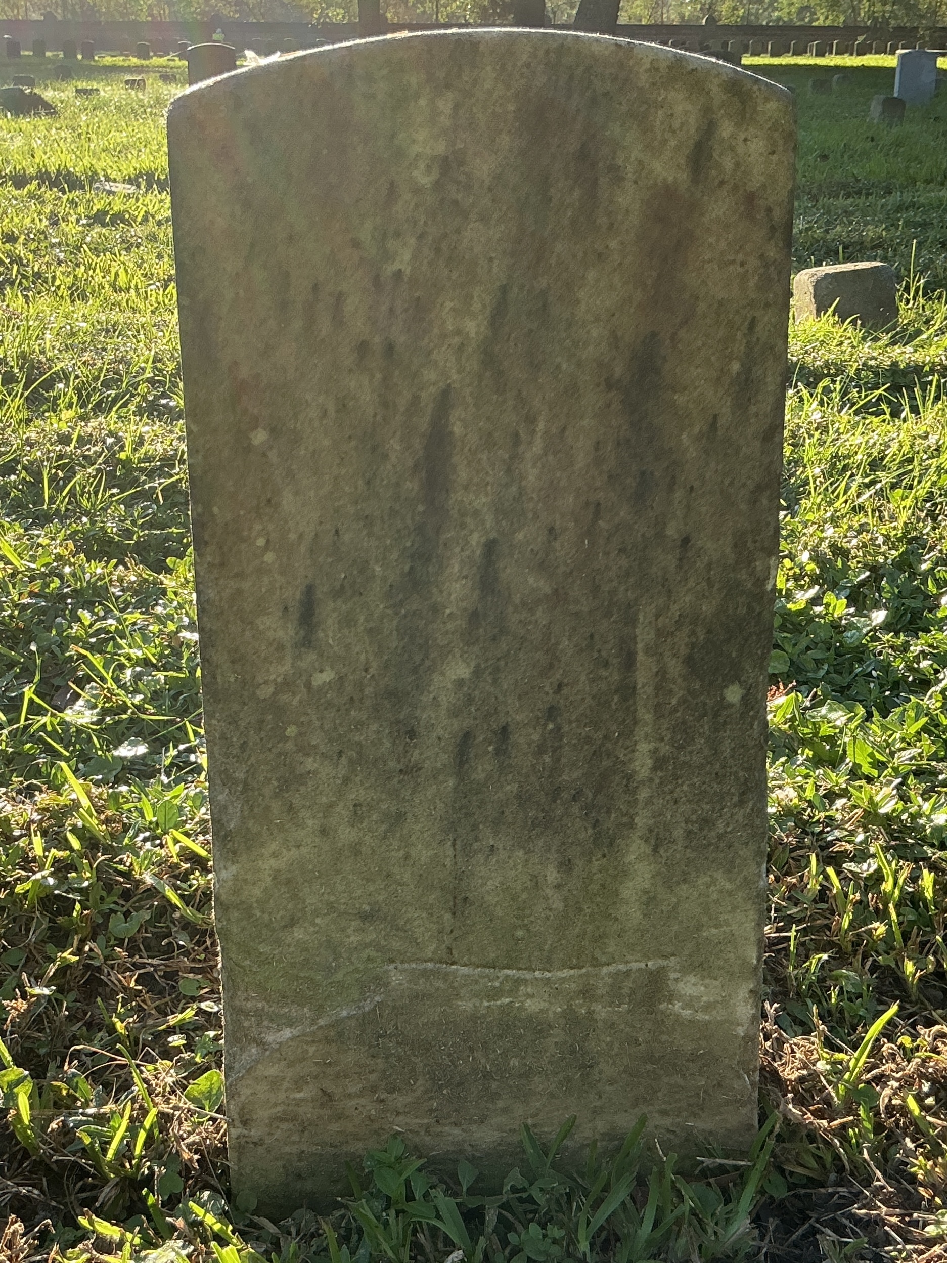 Back of historic upright marble headstone with recessed shield face.