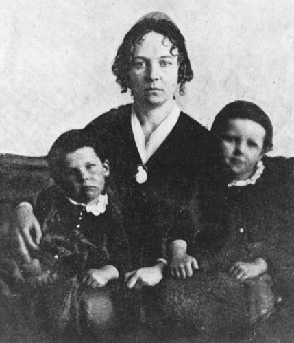 A black-and-white photo of a woman, flanked by two young boys.