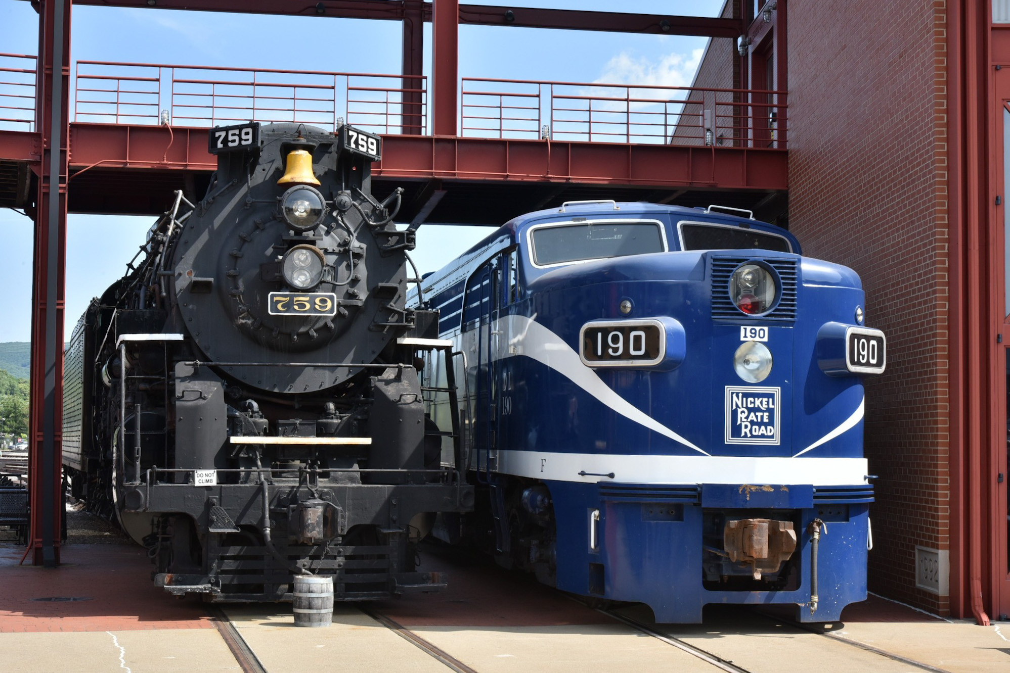 A steam engine parked next to a diesel engine outdoors
