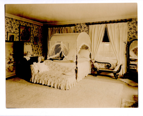Black and white photograph of 19th century guest room featuring empire style furniture.